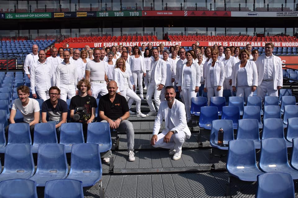 A group picture of the choir in the stadium with the production team in front